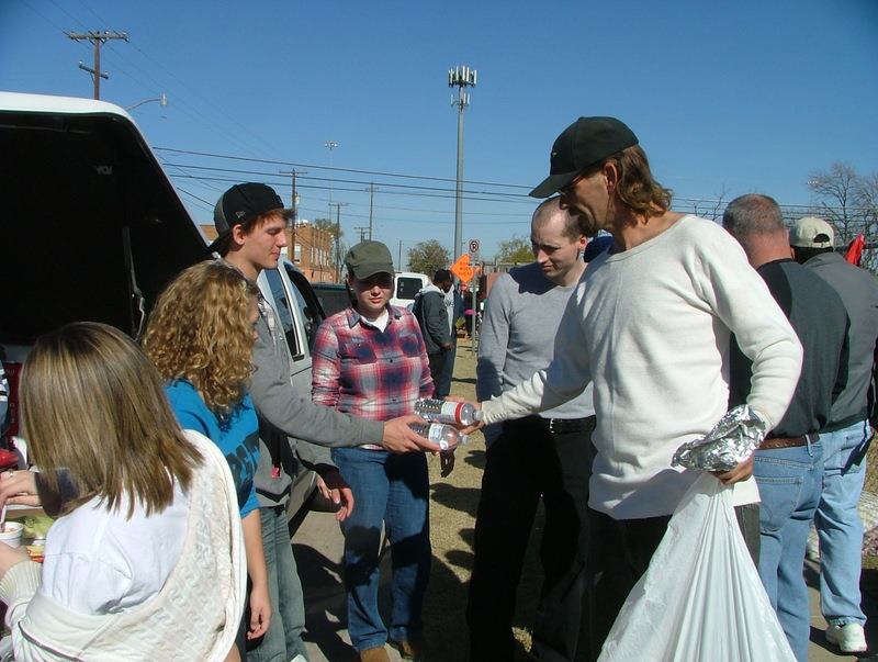 With a warm smile, junior Jared Amos offers a member of the Fort Worth homeless shelter water.