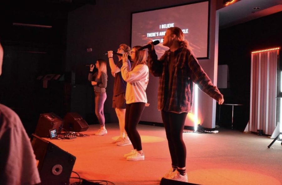 Junior Brayden Shelton and seniors Carson Wicker, Kenzie Winter and Emilee Talley lead worship at an FCA event.